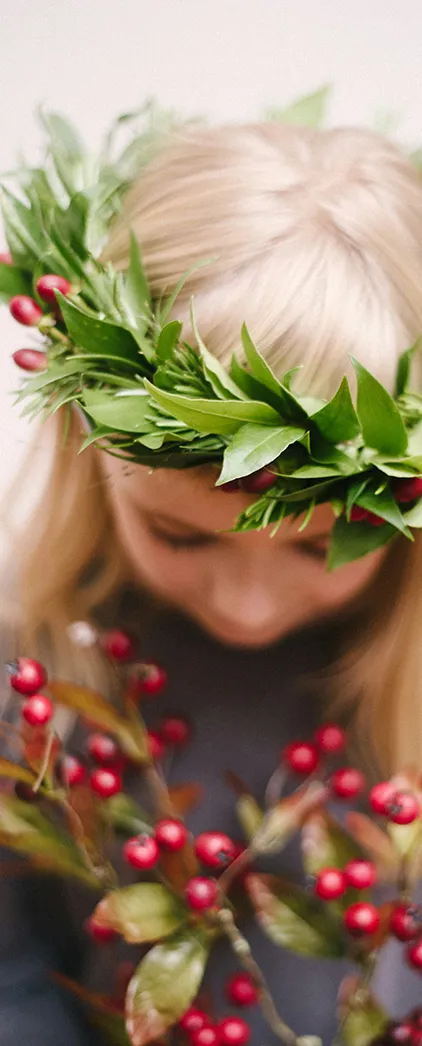 child wearing christmas crown made of leaves and red berries